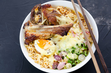 Japanese ramen noodle soup with pork, egg, onion and cheese on dark wooden background