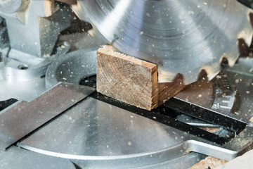 Circumcision of a square board with a circular saw, with slivers flying to the sides, close-up