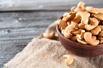 raw cashew nuts in ceramic bowl on wood table