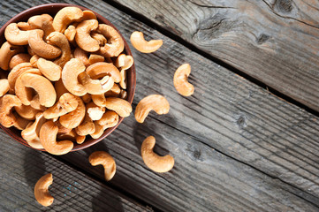Raw cashew nuts in bowl on textured wooden background, table top view, selective focus