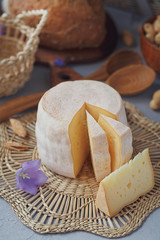 A head of fresh organic cheese served with bread, nuts, white wine and summer flowers.