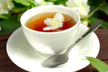 Tea with jasmine in a white cup on a wooden table.