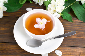 Tea with jasmine in a white cup on a wooden table.