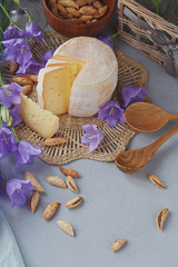 A head of fresh organic cheese served with bread, nuts, white wine and summer flowers.