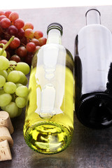 Bottle of white and red wine, grape and corks on wooden table