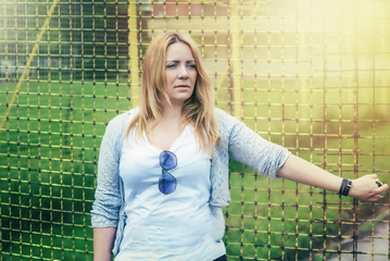 Young woman with long blond hair and grean eyes, posing outside