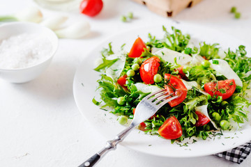 Fresh and healthy fitness salad with lettuce, peas, cherry tomato, cucumber, green onion, dill, sunflower or olive oil and toast on a white background
