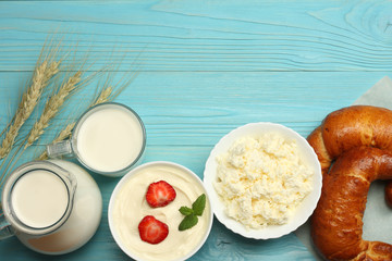 Milk background. Glass jug pitcher of fresh milk with glass, sour cream, cottage cheese and eggs on blue wooden background. Top view with copy space.