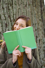 Fototapeta premium Coy young woman hiding behind her book