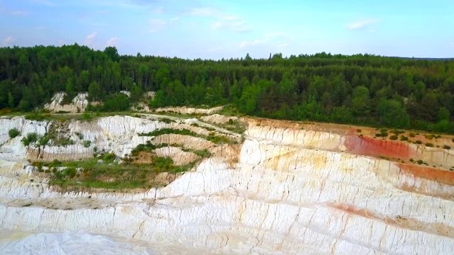 Aerial view of open pit kaolin quarry and factory plant producing ceramic tiles from raw kaolin material. Drone camera flying over industrial area.