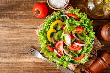 Fresh vegetable salad with greens on wooden table.