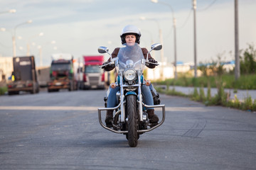 European woman riding chopper motorcycle on asphalt highway, front view