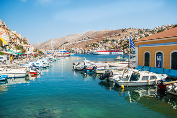 Fototapeta na wymiar Symi, Greece - September 03, 2015: Wonderful Greece. Island Symi, with a turquoise sea, the yachts in the harbor and colorful houses on the slopes of the island