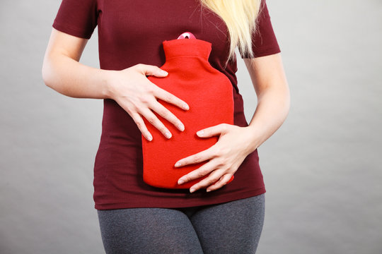 Girl having stomach ache, holding hot water bottle