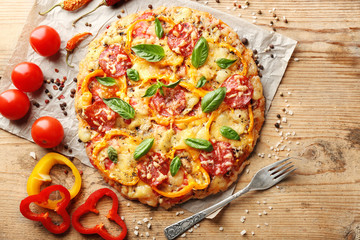 Composition of tasty pizza, vegetables and spices on wooden table