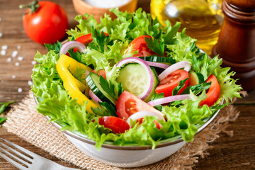 Fresh vegetable salad with greens on wooden table.