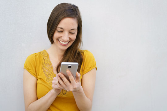 Smiling young woman sending a text message