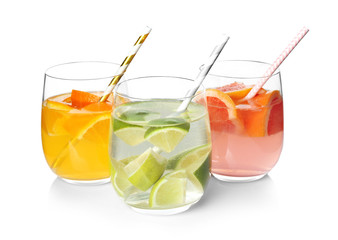 Tasty refreshing lemonade with different fruits in glasses on white background