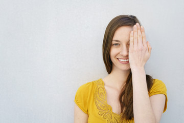 Smiling woman covering an eye with her hand