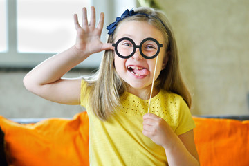 Little girl making face with funny glasses and showing her tongue