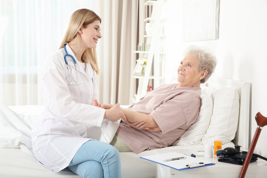 Young nurse examining elderly woman at home