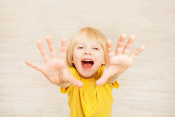 Joyful five years old boy lifting hands upward