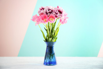 Vase with beautiful tulips on color background