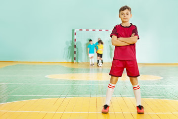 Football player stands confidently in sports hall