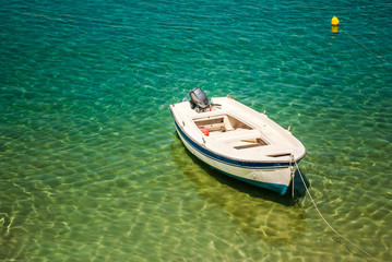 Small white fishing boat, clear sea water and green palm leaves on tropical sea abstract background. Marine landscape.