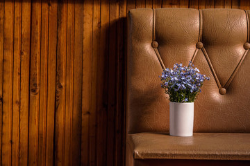a small bouquet of forget-me-nots in a white Cup on wooden background