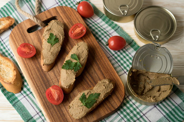 Liver pate on the bread on wooden tray.