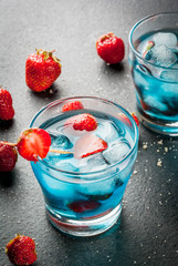 Summer refreshing cocktails, drinks. Strawberry berry colada with fresh berries and blue liqueur. On black stone table. Copy space