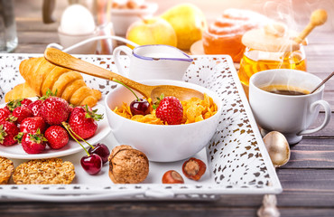 Breakfast with cornflakes berry honey and croissant on wooden