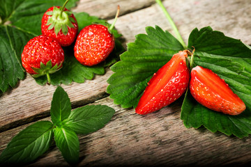 Fresh strawberry with mint lies on a wooden table background. Food in the macro.