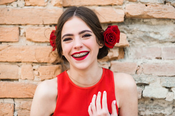 Fototapeta na wymiar fashionable happy woman in red dress with rose in hair