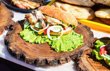 Burger with chicken meat, cheese and fresh vegetables on wooden board. Simple  idea for vegetarian sandwich