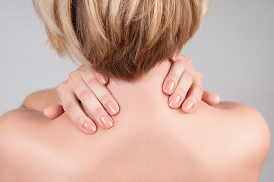 Young woman with shoulder pain, massaging her shoulder