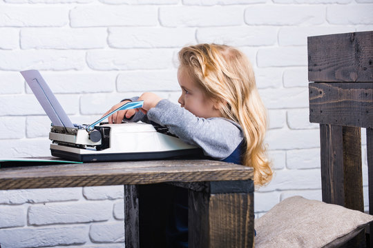 kid sitting at table and typing typewriter with paper