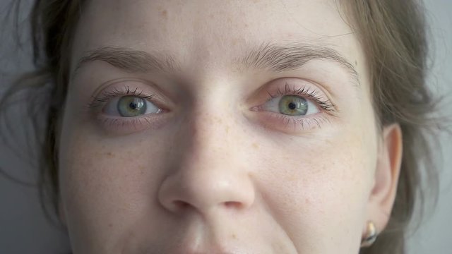 Blond woman squinting her green eyes