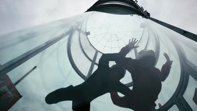 Two skydivers fly into wind tunnel. Extreme skydiving tandem in wind tunnel