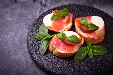Crostini with salmon, mozarella, tomato and basil