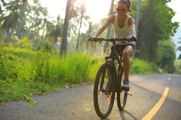 Young  woman cyclist cycling on tropical forest trail