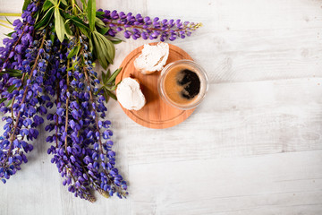 coffee mug served with bruschetta on a wooden Board and lupins flowers on the table