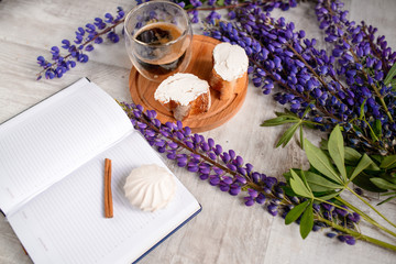 Note with a pen, a calendar and a Cup of coffee served with bruschetta, lupins flowers on wooden table