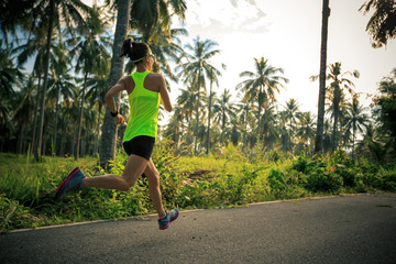 Young fitness woman running at tropical forest trail