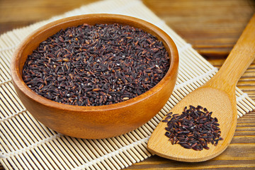 Raw black rice in bowl on  wooden background