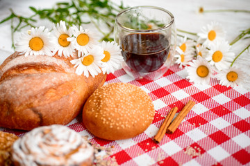 Cup of coffee served with biscuits and buns on wooden background