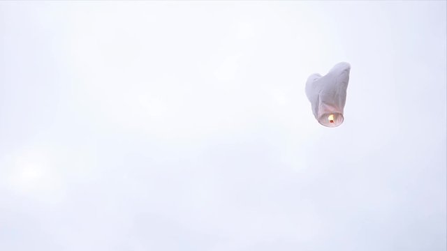 The heart shaped white sky lantern flying in the sky. Traditional asian sky lantern