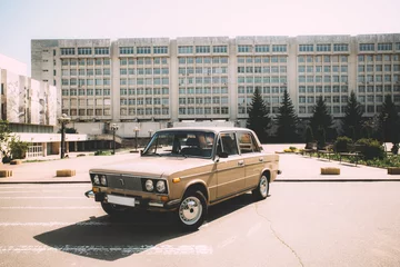 Fotobehang Een retro auto gemaakt in de USSR staat op de achtergrond van het Kiev Polytechnic Institute. Kiev, Oekraïne. © Elizaveta