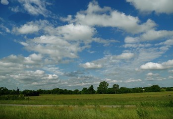 Obraz premium Beautiful cotton clouds hang above a green countryside 
